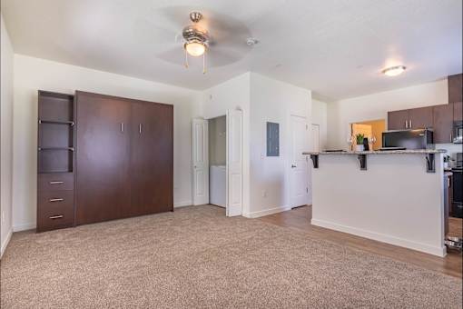 A spacious living room with a ceiling fan and a kitchen area with a microwave and oven at Riverplace Apartment Homes, Independence, OR