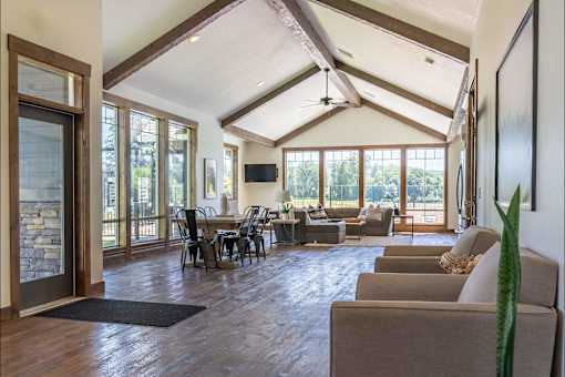 A living room with a stone wall and a ceiling fan at Riverplace Apartment Homes, Independence, 97351