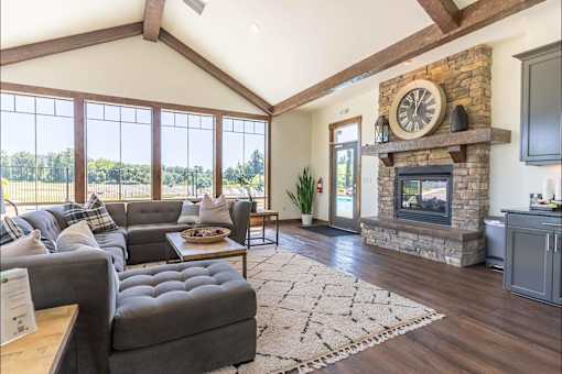 A living room with a grey couch and a stone fireplace at Riverplace Apartment Homes, Independence, Oregon