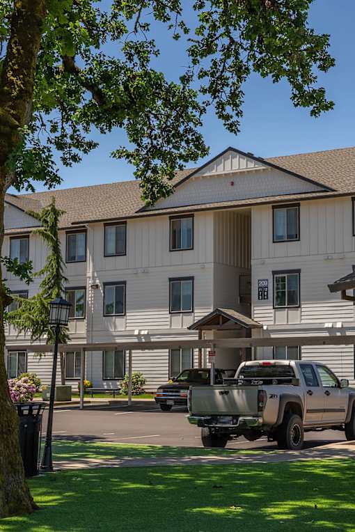 A large white building with a brown roof and a truck parked in front at Riverplace Apartment Homes, Independence, OR