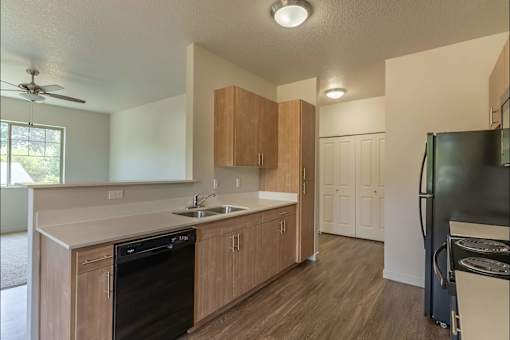 A kitchen with wooden cabinets and a black dishwasher at Sandyplace Apartment Homes, Sandy, OR, 97055