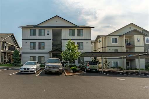 A white and beige two story apartment building with a parking lot in front at Sandyplace Apartment Homes, Sandy, Oregon
