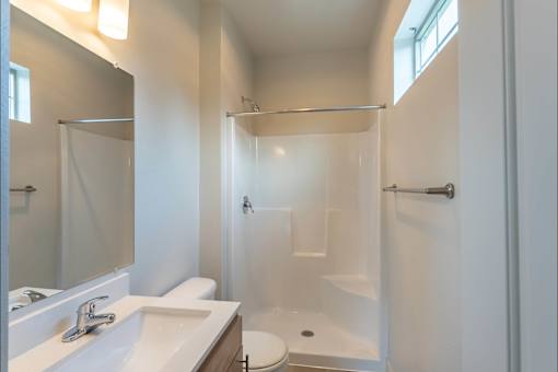 A white bathroom with a toilet, sink, and shower at Sandyplace Apartment Homes, Oregon