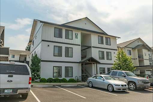 A white two-story building with a parking lot in front at Sandyplace Apartment Homes, Sandy, OR