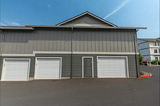 A grey building with three white garage doors at Sandyplace Apartment Homes, Sandy, OR, 97055