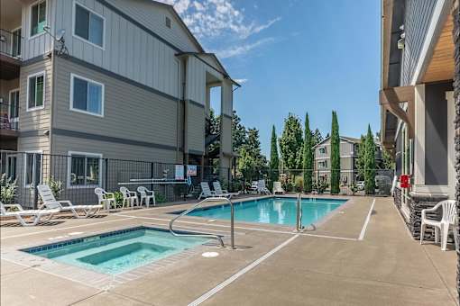 A swimming pool surrounded by lounge chairs and apartment buildings at Silverplace Apartment Homes, Oregon, 97381