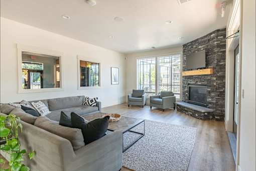 A living room with a grey couch and a stone fireplace at Silverplace Apartment Homes, Silverton, 97381