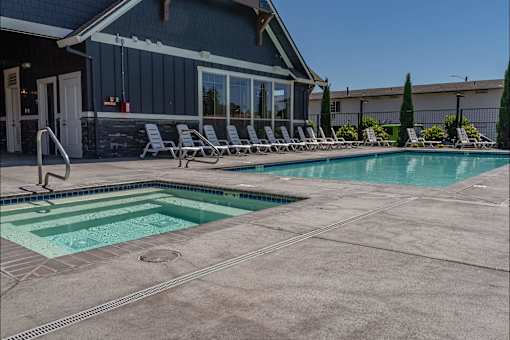 A pool with a slide and lounge chairs outside a house at St Helens Place Apartment Homes, St Helens, 97051