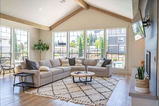 A living room with a couch, a coffee table, and a TV at St Helens Place Apartment Homes, Oregon