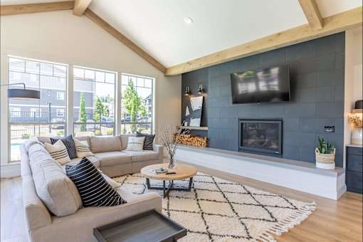 A modern living room with a grey couch, a black and white rug, and a fireplace at St Helens Place Apartment Homes, Oregon, 97051