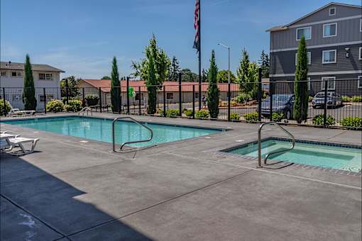 A swimming pool surrounded by a fence and trees at St Helens Place Apartment Homes, Oregon, 97051