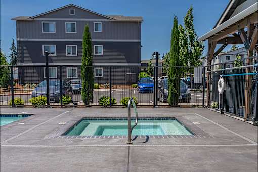 A swimming pool in a backyard with a building in the background. at St Helens Place Apartment Homes, St Helens, OR
