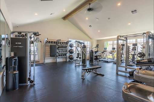 A spacious gym with various exercise equipment and a bench at St Helens Place Apartment Homes, St Helens, 97051
