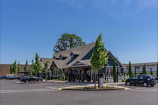 A building with a green roof and a parking lot in front. at St Helens Place Apartment Homes, St Helens, 97051