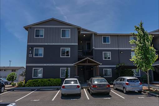 A grey apartment building with a parking lot in front at St Helens Place Apartment Homes, Oregon, 97051