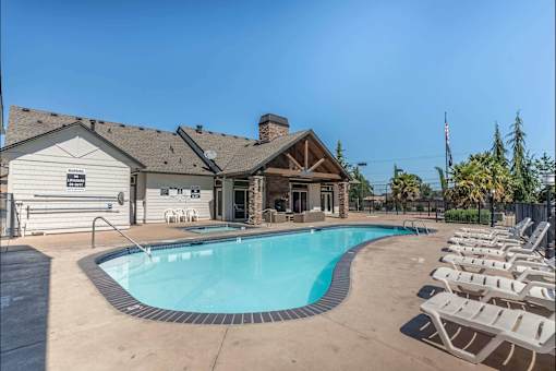 A pool with chairs around it and a building in the background at Stoneplace Apartment Homes, Molalla, OR, 97038