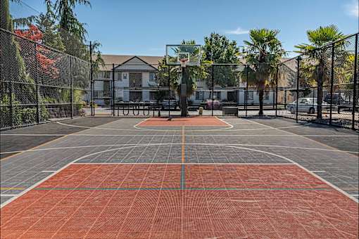 A basketball court with a red surface and a basketball hoop in the middle at Stoneplace Apartment Homes, Molalla, OR