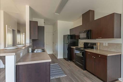 A modern kitchen with dark wood cabinets and appliances at Stoneplace Apartment Homes, Oregon