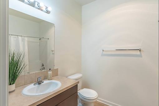 A bathroom with a sink, toilet, mirror, and a plant at Stoneplace Apartment Homes, Molalla, Oregon