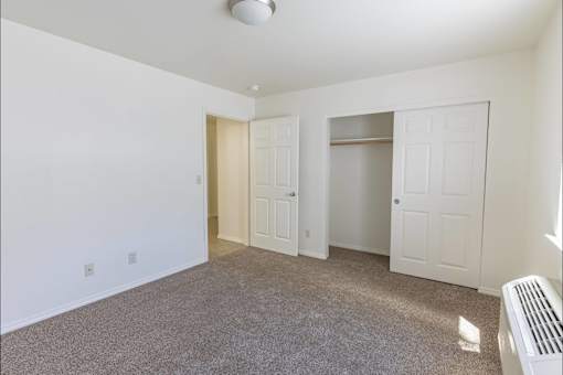 A room with a carpeted floor and a heater on the wall at Stoneplace Apartment Homes, Molalla, OR