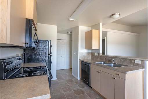A kitchen with a black stove top oven and a black refrigerator at Stoneplace Apartment Homes, Molalla, 97038