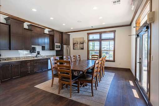 A kitchen with dark wood cabinets and a dining table with chairs at Stoneplace Apartment Homes, Molalla