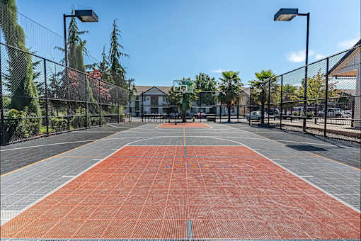 A tennis court with a net and a building in the background at Stoneplace Apartment Homes, Molalla, 97038