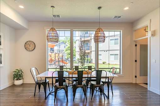 A dining room with a table and chairs and a clock on the wall at Timberridge Place Apartment Homes, Albany, Oregon