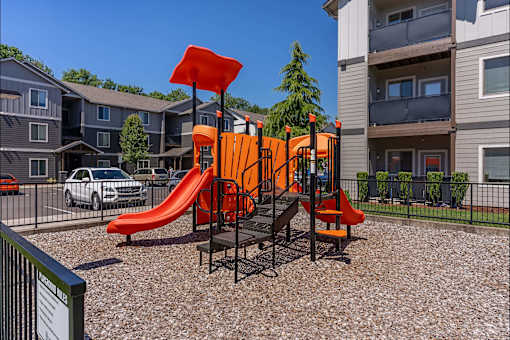 A playground with a red slide and orange structure at Timberridge Place Apartment Homes, Albany, Oregon