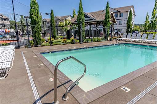 A pool surrounded by a fence and trees at Timberridge Place Apartment Homes, Albany, 97322
