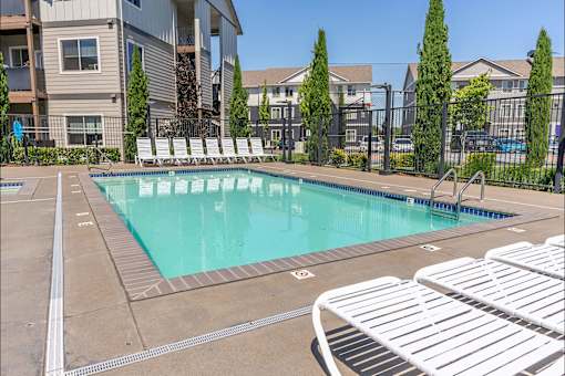 A swimming pool surrounded by white lounge chairs at Timberridge Place Apartment Homes, Oregon