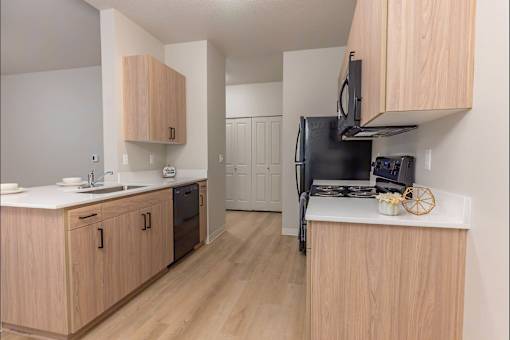 A kitchen with wooden cabinets and a black fridge at Woodburn Place Apartment Homes, Woodburn, 97071