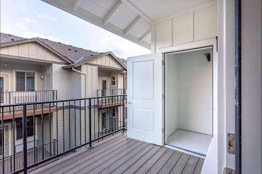 A balcony with a white door and black railings at Woodburn Place Apartment Homes, Oregon