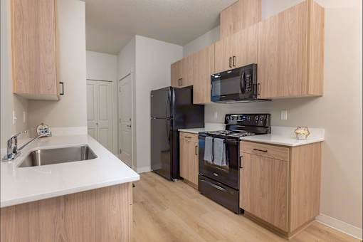 A kitchen with wooden cabinets and black appliances at Woodburn Place Apartment Homes, Woodburn