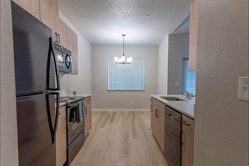A kitchen with a black refrigerator and wooden floors at Woodburn Place Apartment Homes, Oregon, 97071
