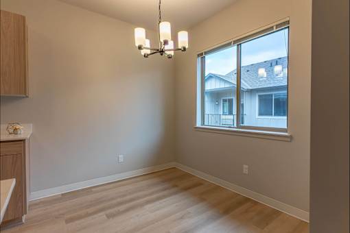 A room with wooden floors and a window overlooking a house at Woodburn Place Apartment Homes, Woodburn, 97071