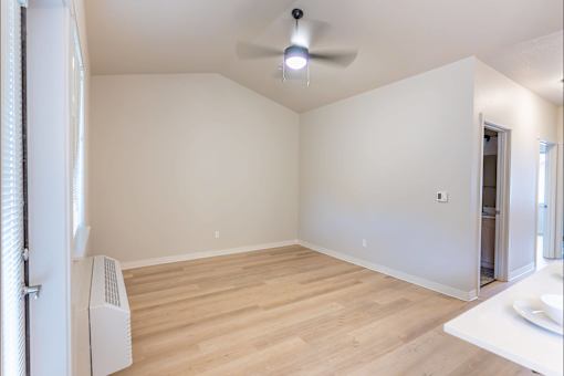 A room with a ceiling fan and a window with blinds at Woodburn Place Apartment Homes, Woodburn, Oregon