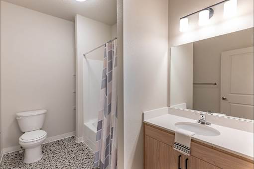 A white toilet sits next to a sink in a bathroom at Woodburn Place Apartment Homes, Woodburn, OR