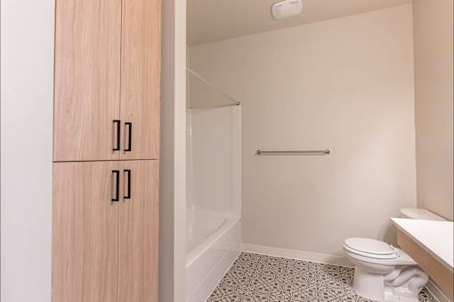 A bathroom with a toilet, sink, and wooden cabinet at Woodburn Place Apartment Homes, Oregon