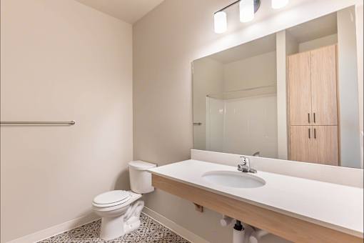 A white toilet sits in a bathroom next to a sink at Woodburn Place Apartment Homes, Oregon, 97071