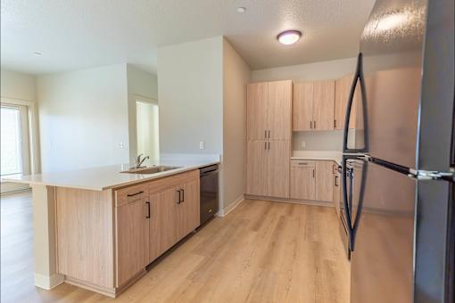 A kitchen with wooden cabinets and a refrigerator at Woodburn Place Apartment Homes, Woodburn, OR, 97071