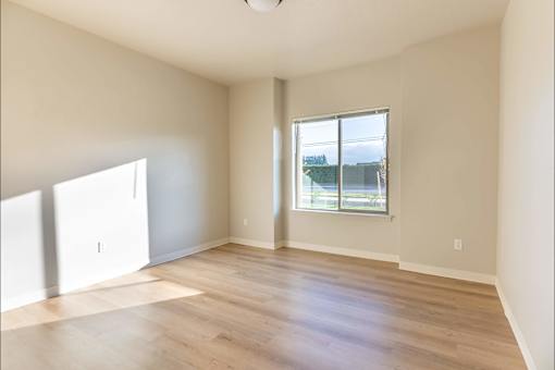 A room with a large window and wooden flooring at Woodburn Place Apartment Homes, Woodburn, Oregon