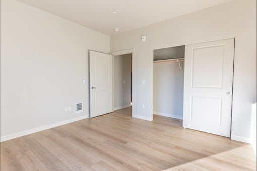 A room with white walls and wooden flooring with two doors at Woodburn Place Apartment Homes, Woodburn, Oregon