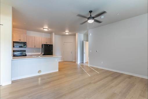A room with a ceiling fan and wooden floors at Woodburn Place Apartment Homes, Woodburn