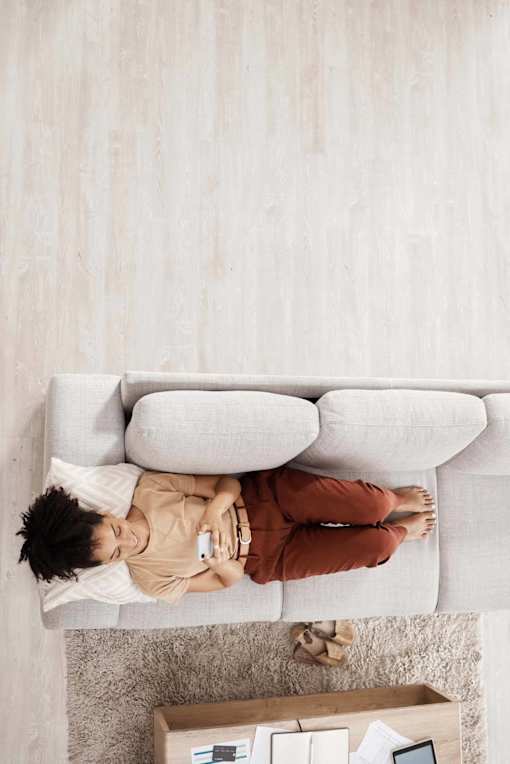 A person is lying on a grey couch with a remote control in hand at The Hub Hermiston Apartments, Hermiston, 97838