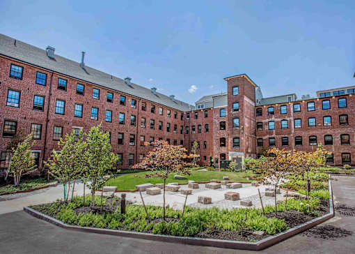 A courtyard with a garden in front of a red brick building.