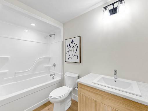 A white bathroom with a toilet, sink, and bathtub.