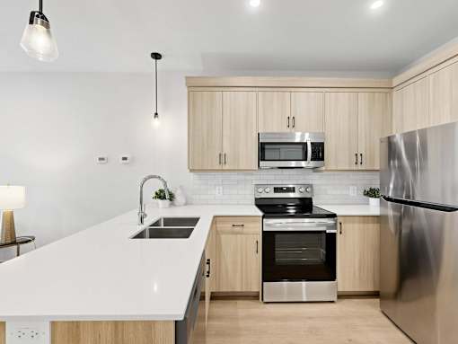 A modern kitchen with a white countertop and stainless steel appliances.