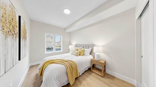 A bedroom with a bed, nightstand, and a painting on the wall.