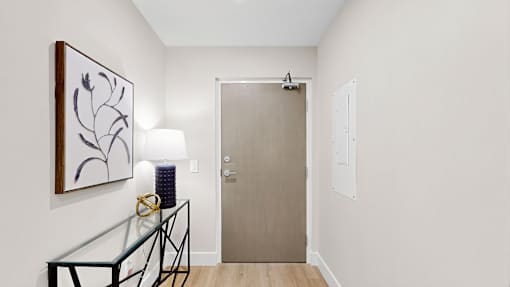 A hallway with a glass table and a painting on the wall.